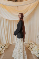 Black Satin Shirt with Wavy Embroidered Hem styled with White Chiffon Skirt with Black Floral Print — full-length side view