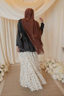 Black Satin Shirt with Wavy Embroidered Hem styled with White Chiffon Skirt with Black Floral Print — back view, walking pose
